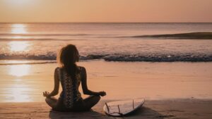 A girl doing yoga by the beach before going out for s surf.
